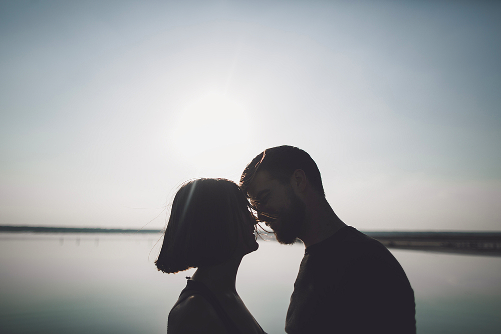 Silhouette of Caucasian couple face to face at lake