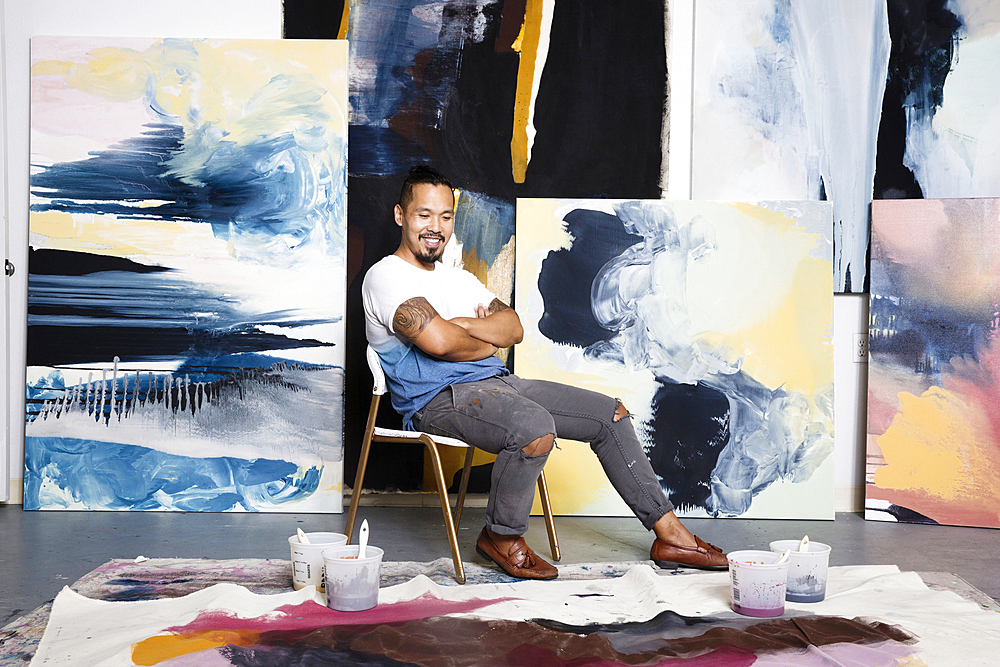 Pacific Islander painter admiring canvas on floor