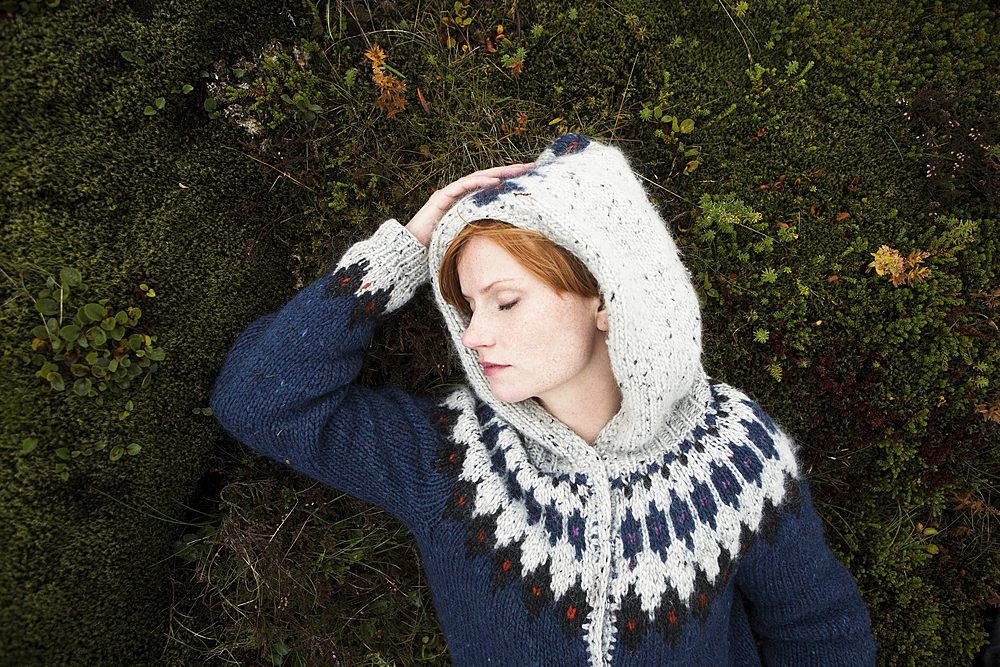 Caucasian woman wearing sweater laying on moss