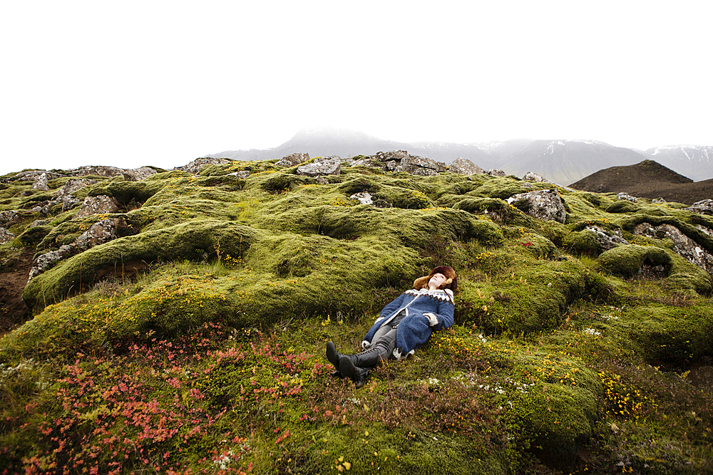 Caucasian woman laying on mossy rocks