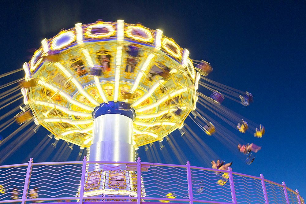 Illuminated spinning amusement park ride at night