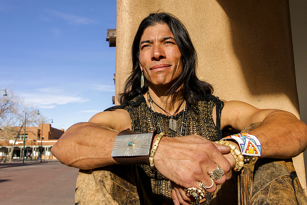 Native American man sitting against post