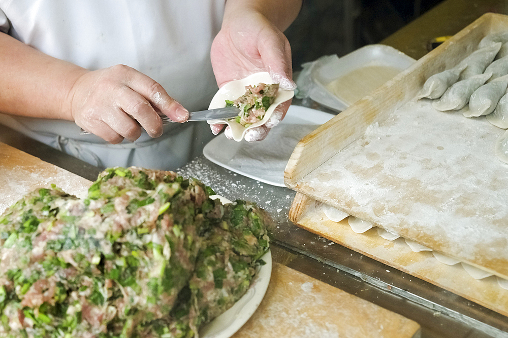 Chef spreading filling in dumpling