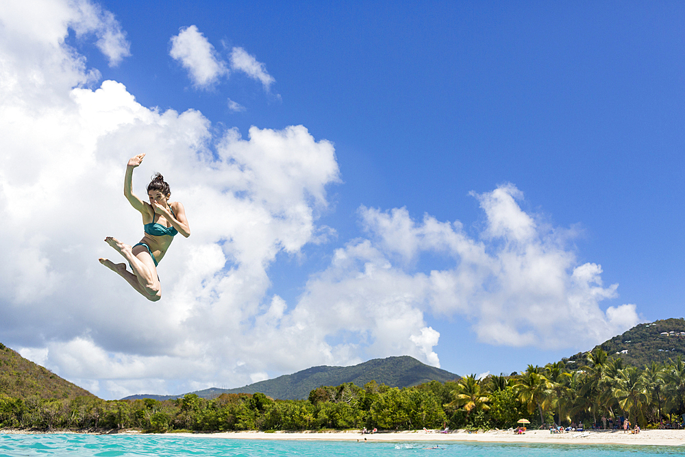 Caucasian woman jumping into tropical ocean