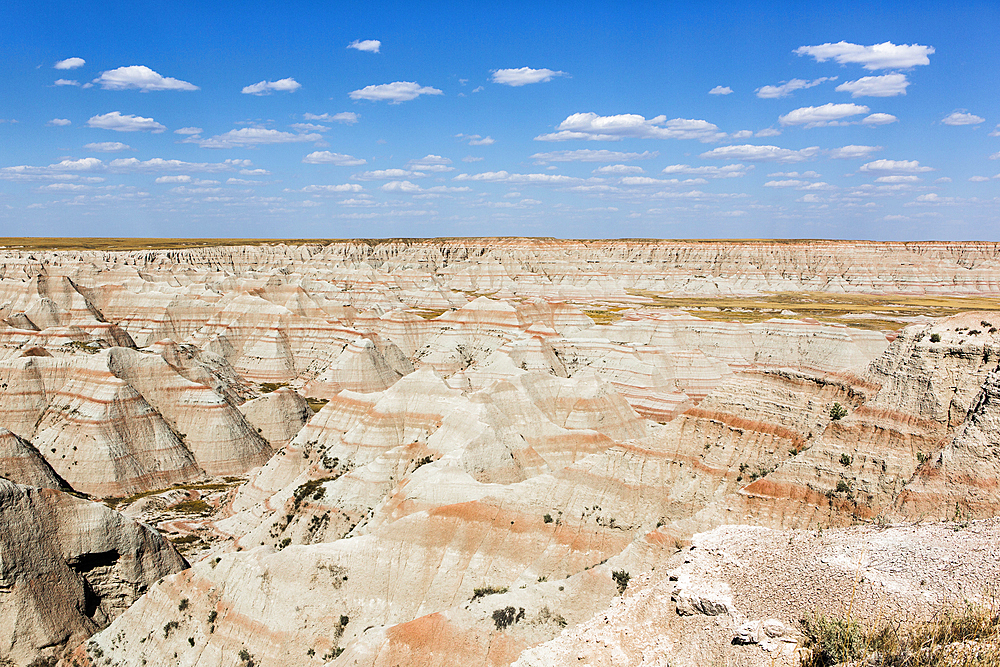 Layered rock formations under blue sky, Badlands National Park, South Dakota, United States