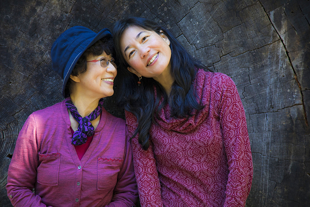 Older Japanese mother and daughter posing at tree slice