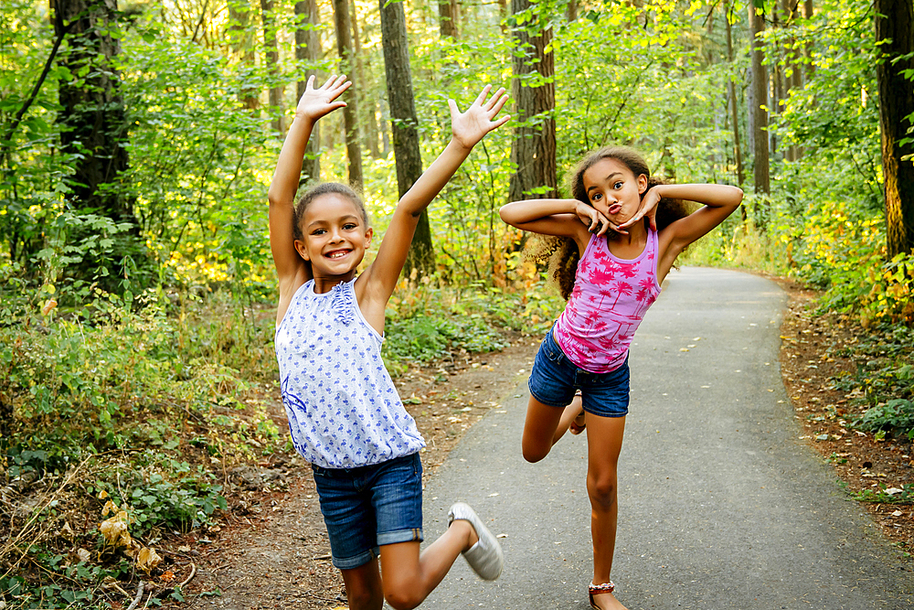 Mixed Race sisters having fun posing on forest path