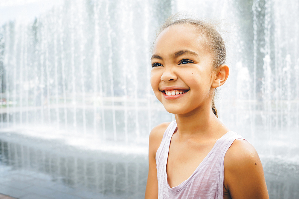 Smiling Mixed Race girl near fountain