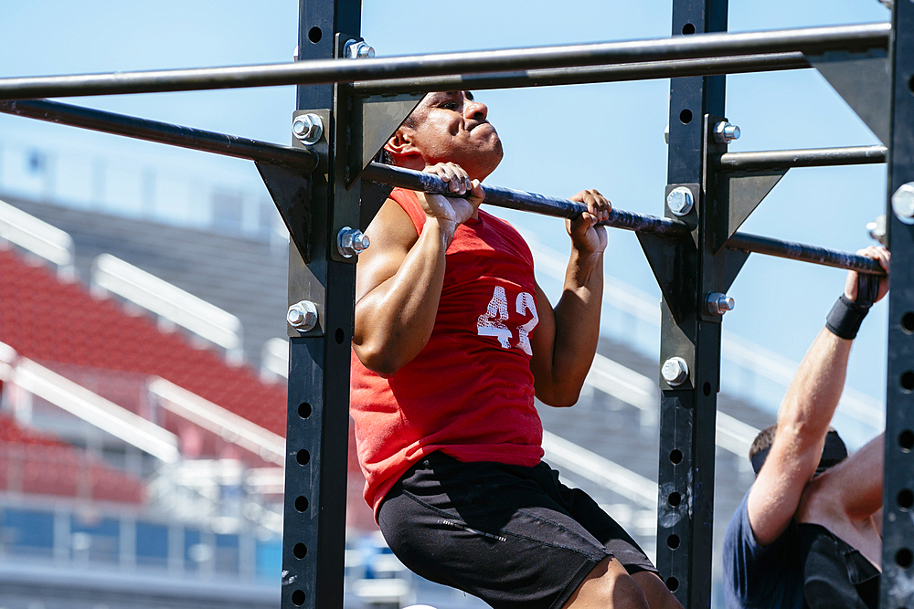 Hispanic man doing chin-ups outdoors