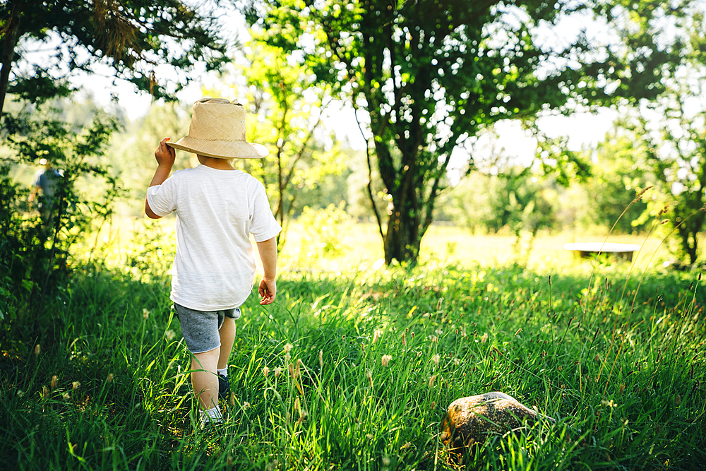 Caucasian boy wearing hat walking in grass