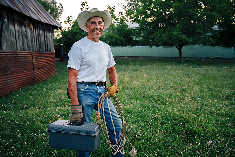 Caucasian farmer carrying rope and toolbox