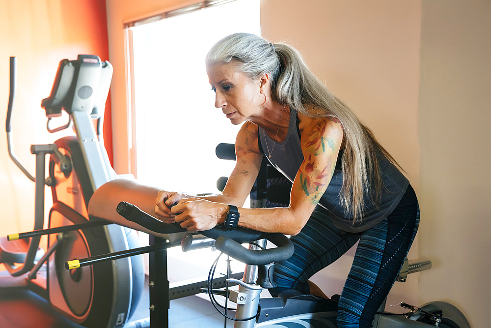 Caucasian woman riding stationary bicycle in gymnasium