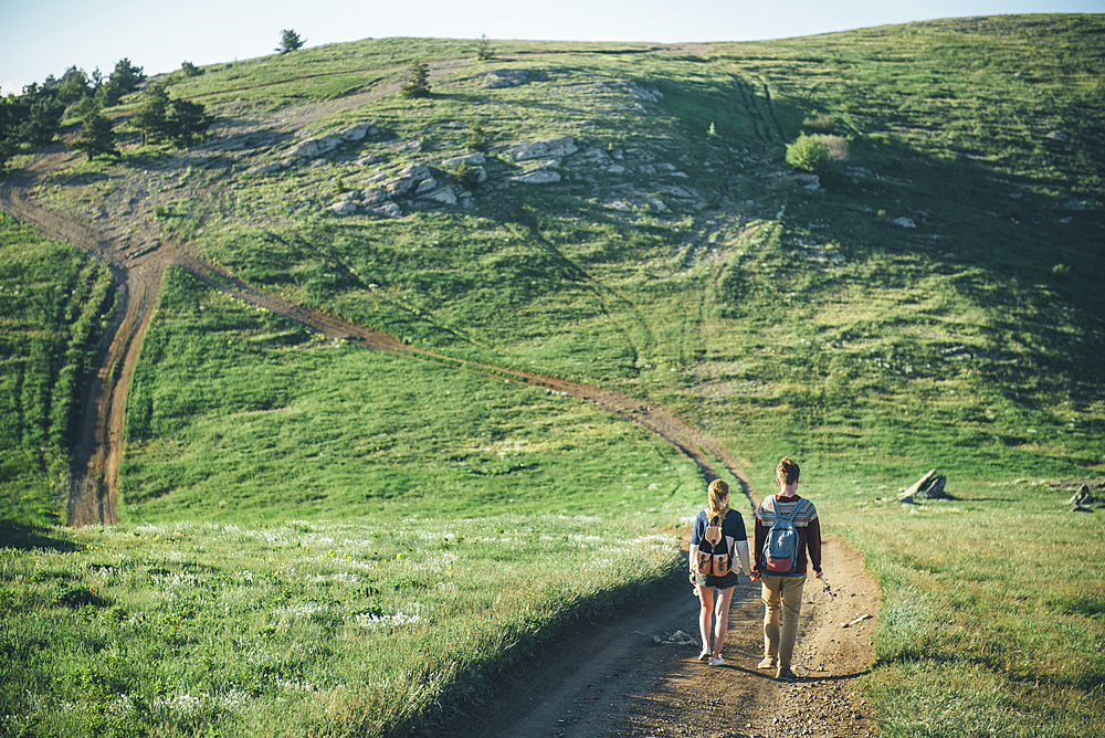 Caucasian couple walking on path toward hill