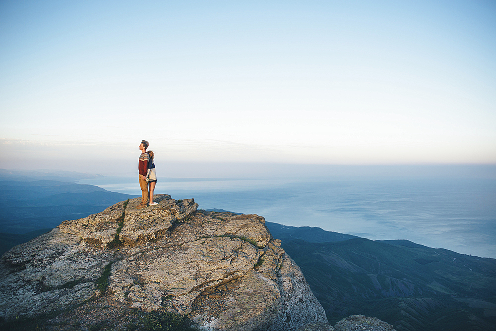 Caucasian couple standing back to back on mountain