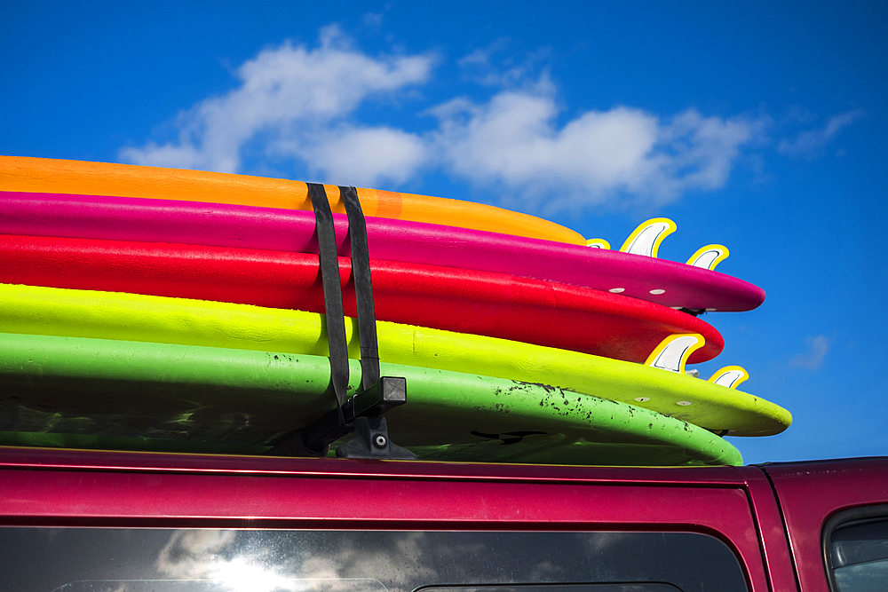 Multicolor surfboards strapped to roof of car