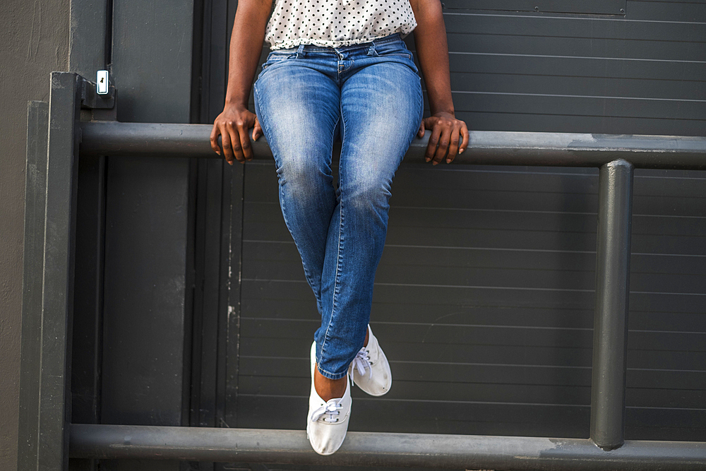 Legs of African American woman sitting on railing