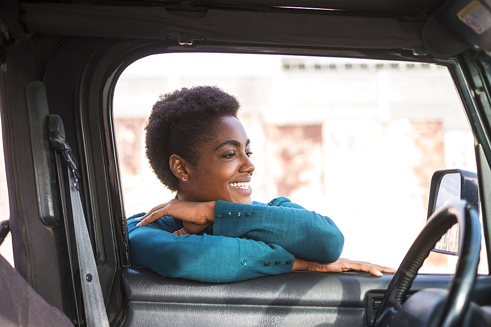 Smiling African American woman leaning on car window