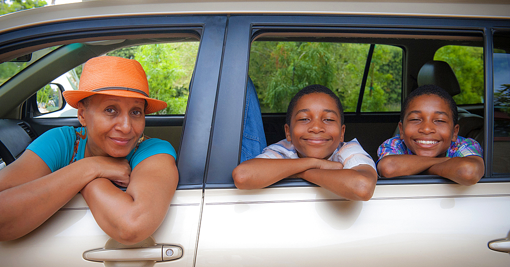 Portrait of mother and twin sons leaning on car windows