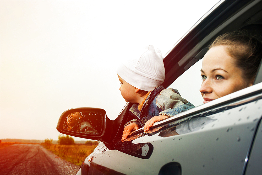 Caucasian mother and son looking out car window