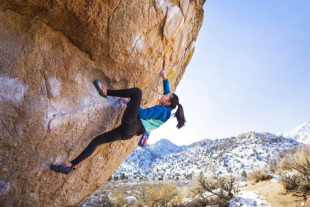 Mixed Race girl climbing rock