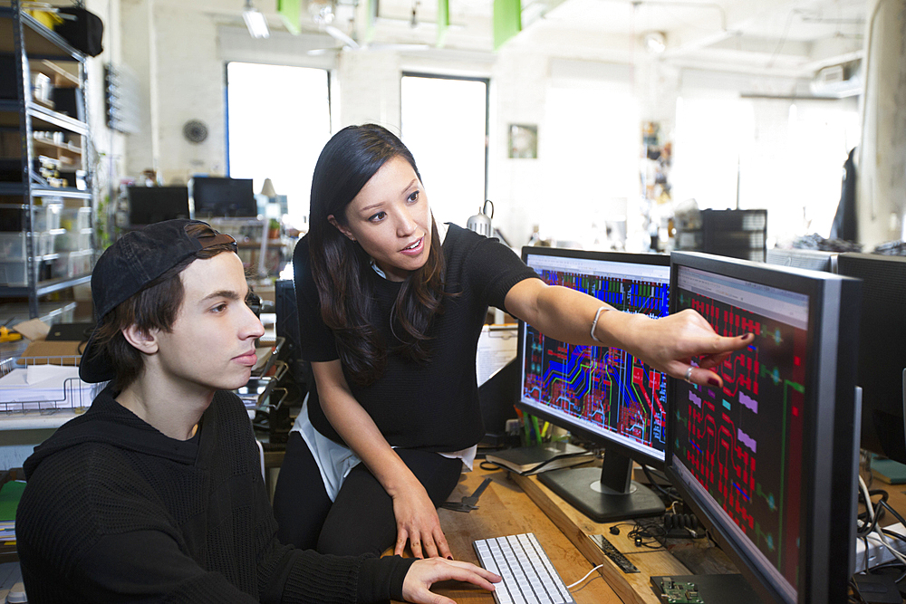 Man and woman examining circuits on computer monitors