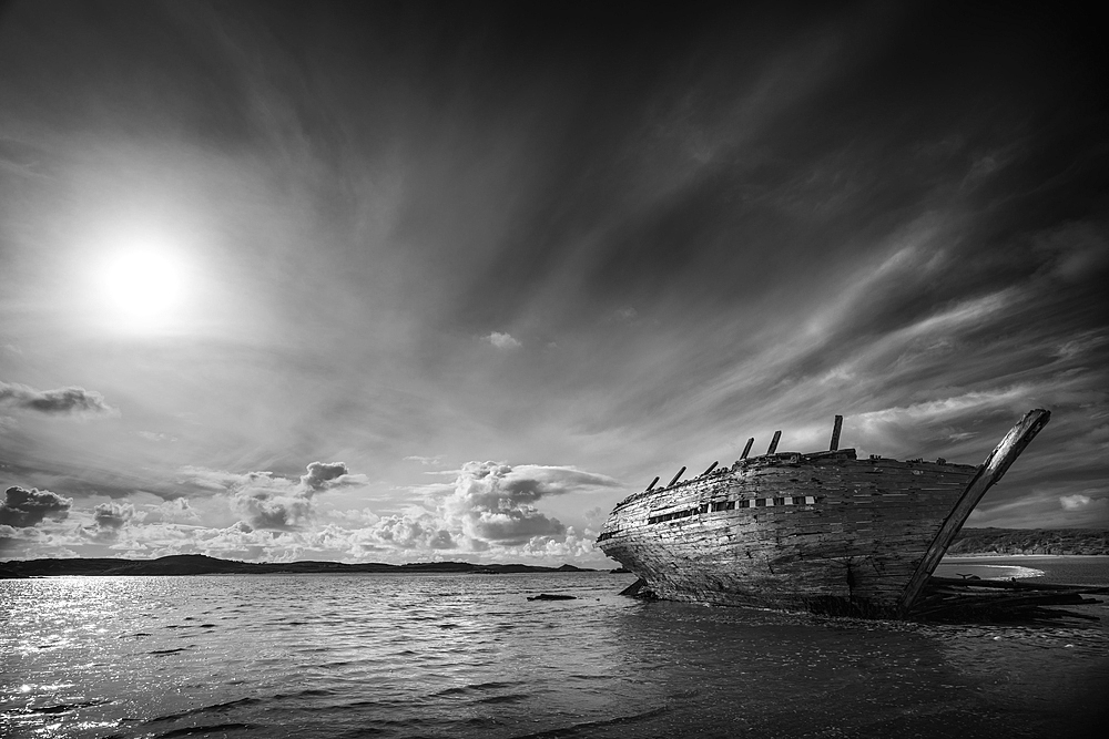 Shipwreck on beach under clouds