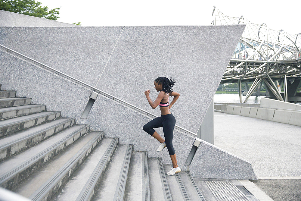 Mixed Race woman running up urban staircase