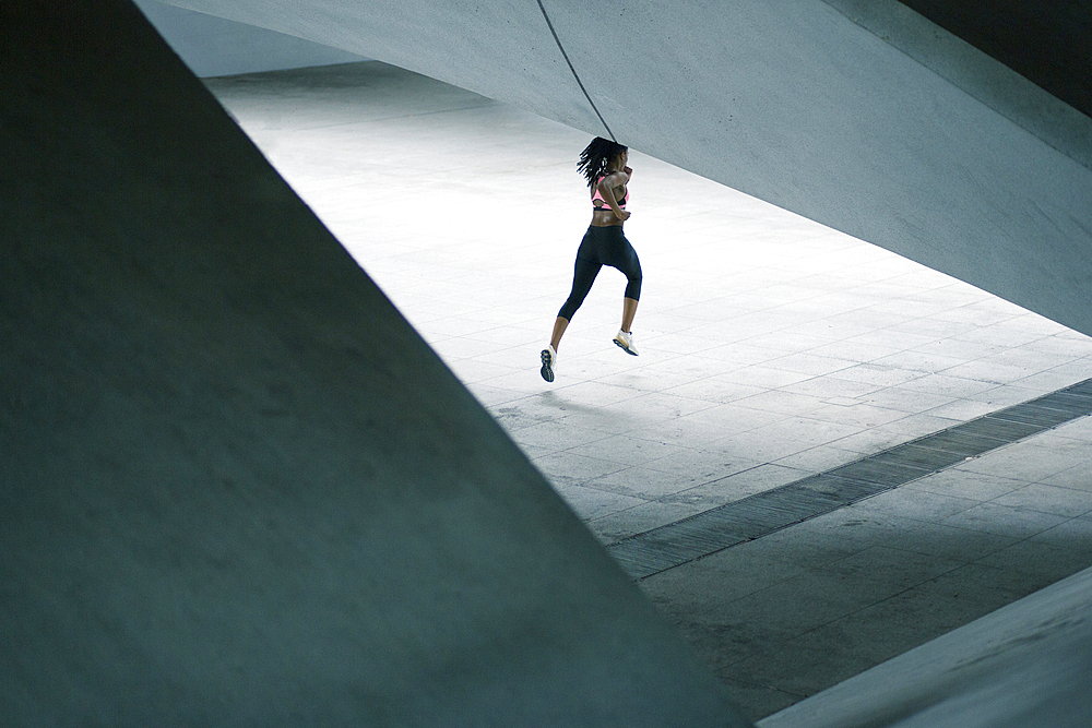 Mixed Race woman running under urban structure