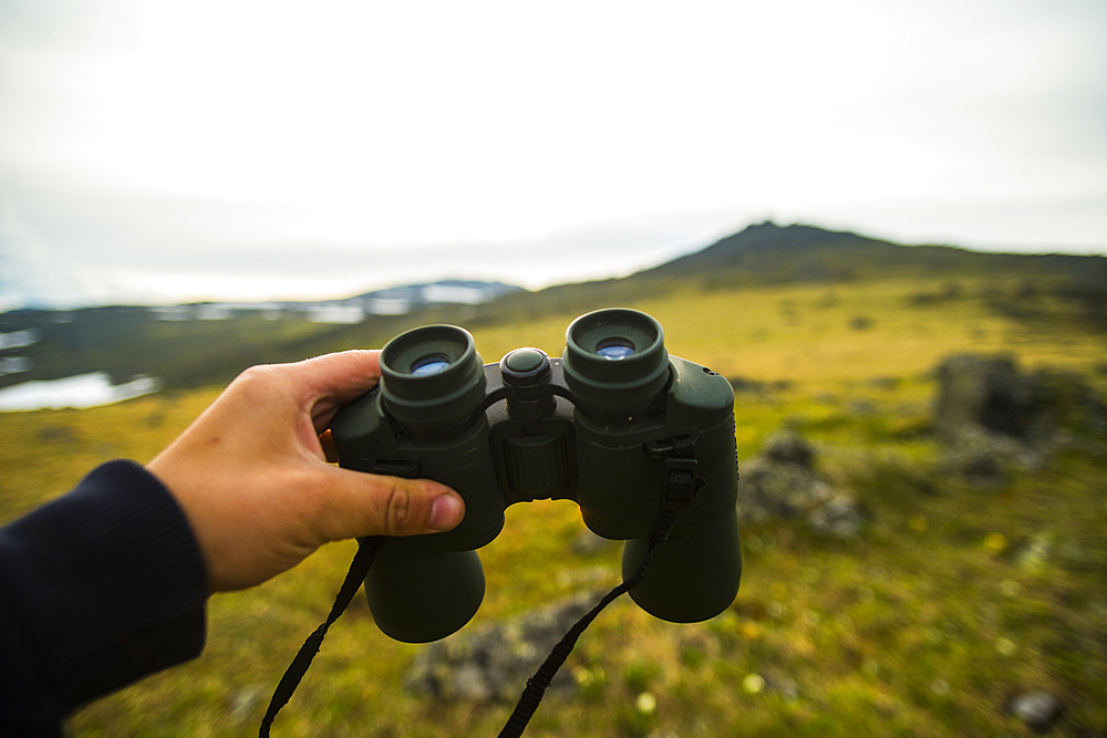 Hand of man holding binoculars outdoors