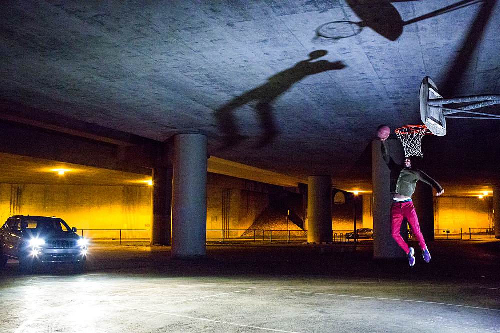 Headlights shining on Black man dunking basketball