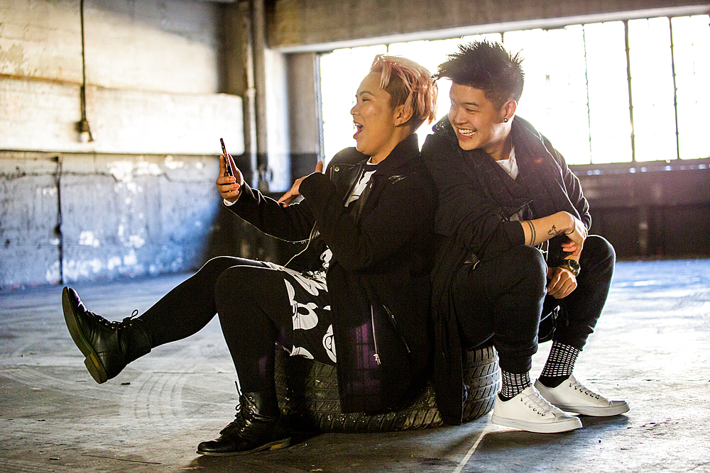 Androgynous Asian man and woman posing for cell phone selfie