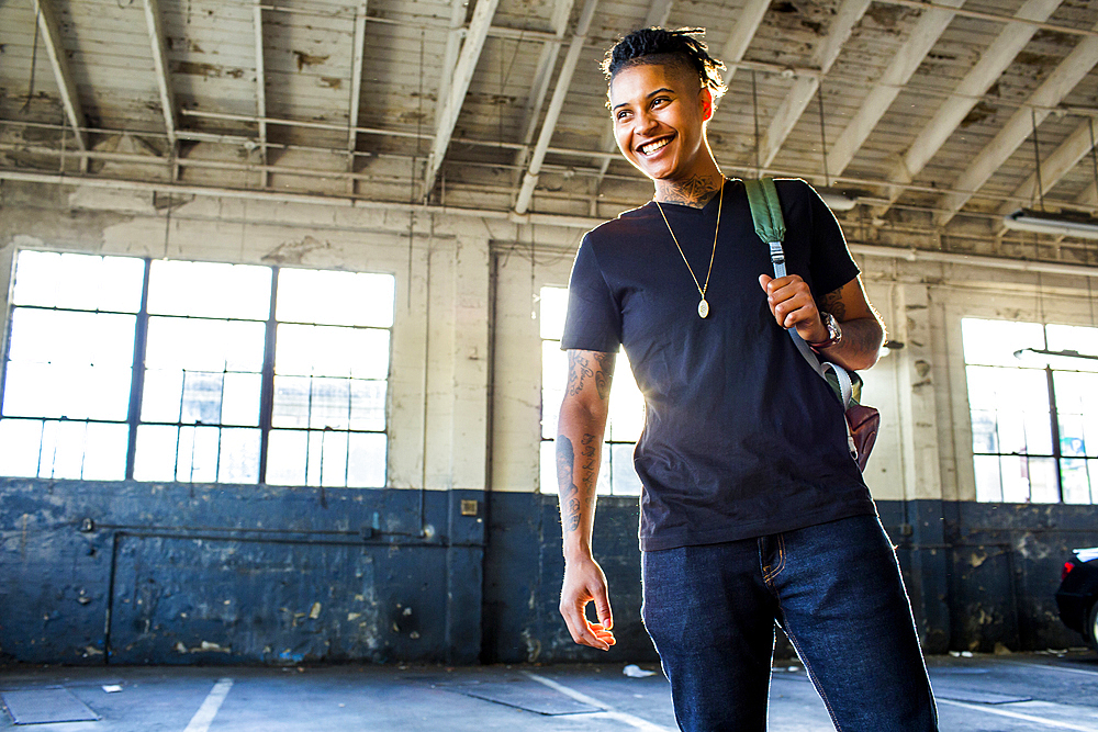 Smiling androgynous Mixed Race woman carrying backpack