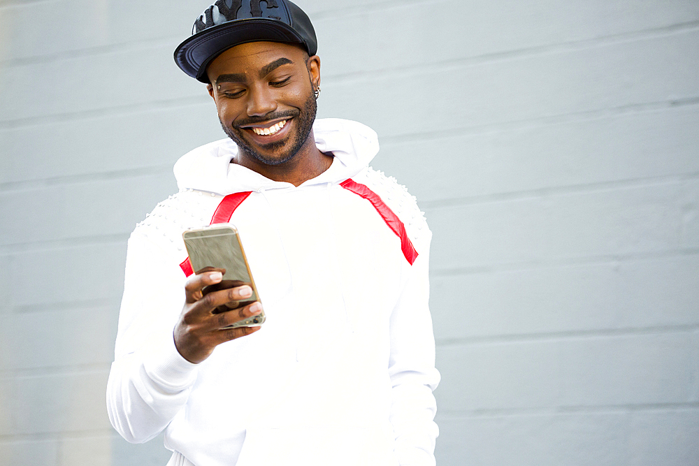 Smiling Black man texting on cell phone