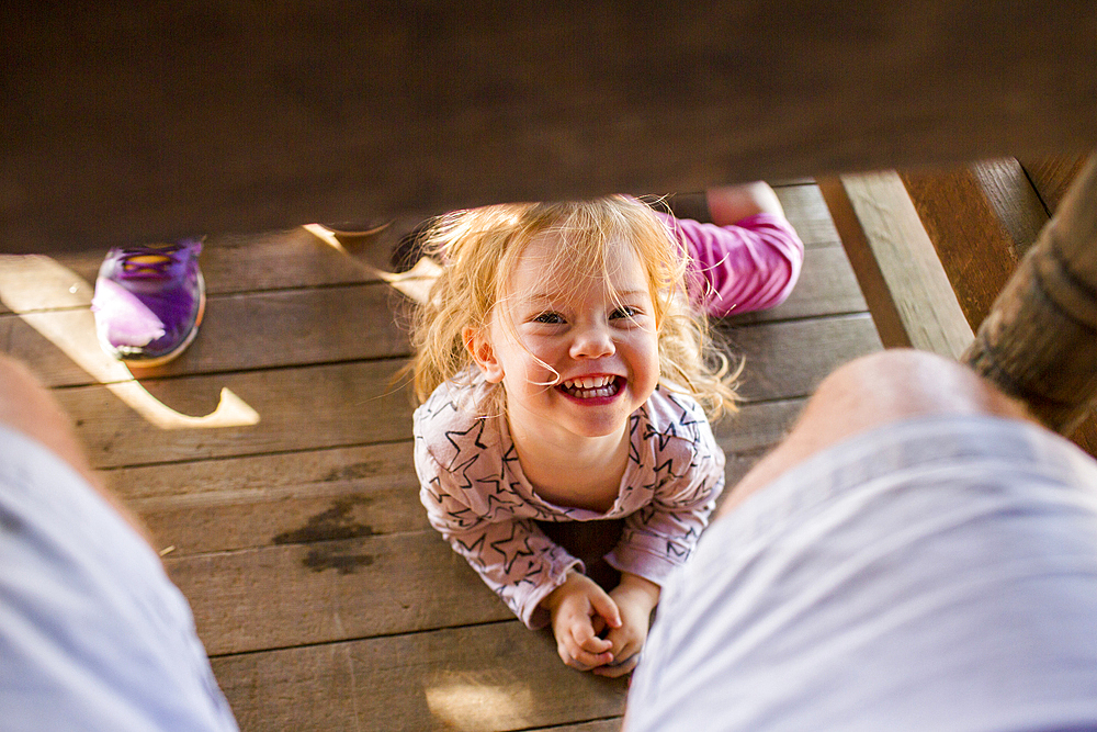 Portrait of smiling Caucasian girl laying underneath table