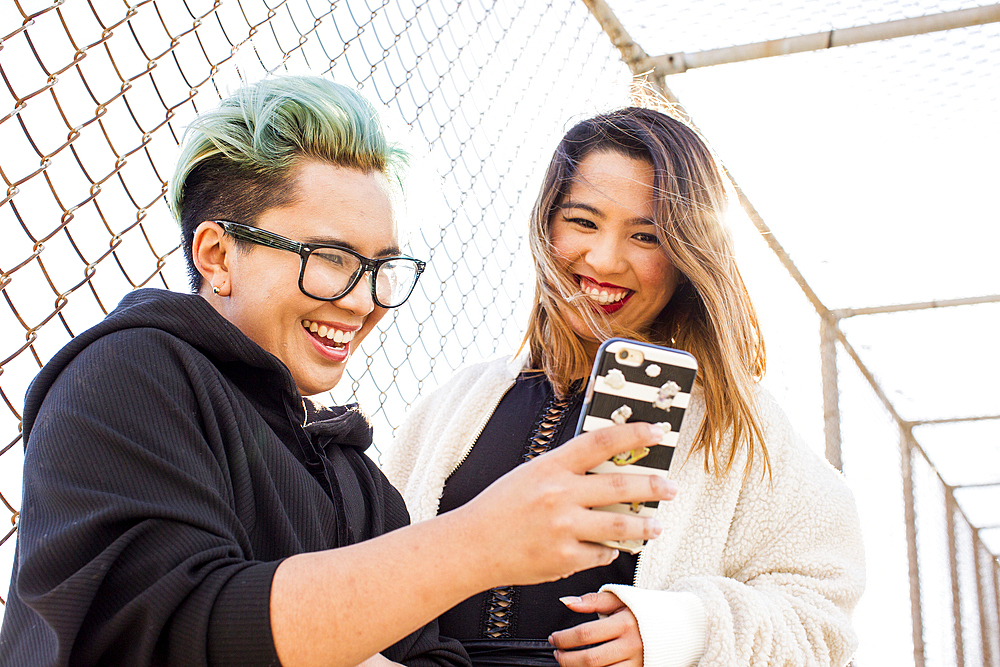 Smiling Asian women posing for cell phone selfie