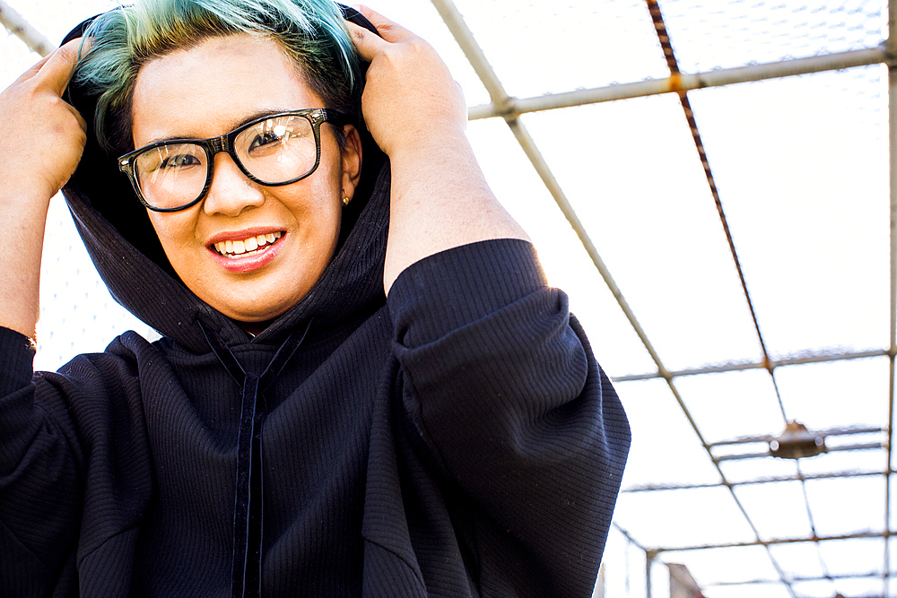 Portrait of smiling androgynous Asian woman wearing hoodie