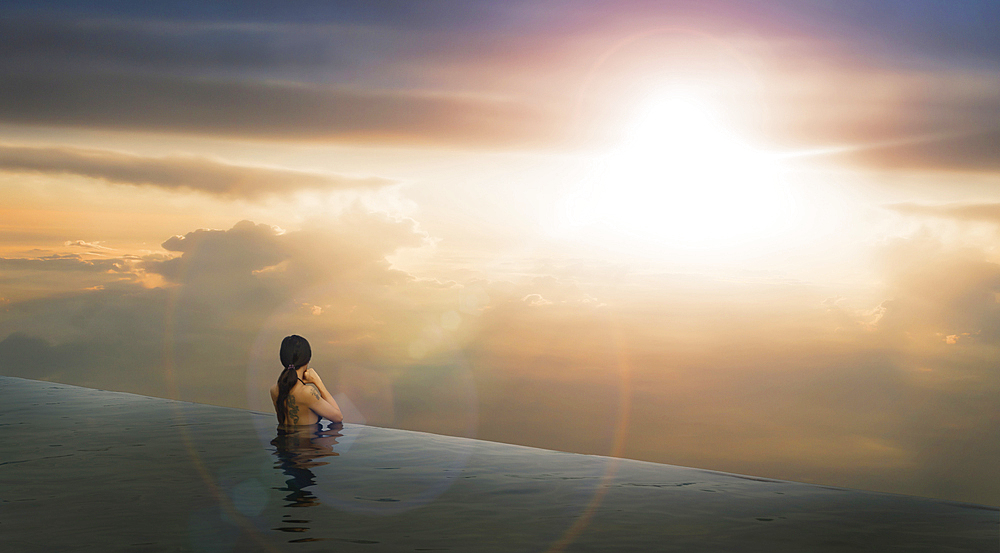 Chinese woman in infinity pool admiring sunset