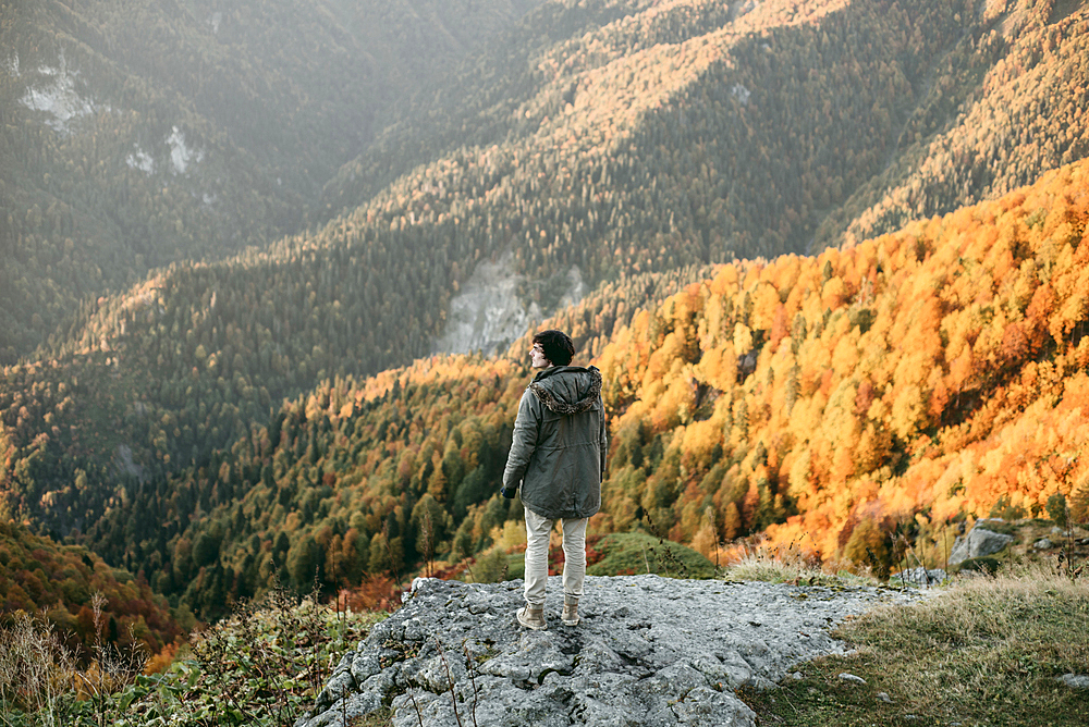 Caucasian man standing on mountain rock overlooking valley