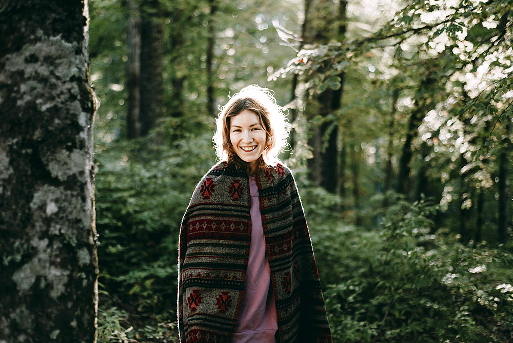 Smiling Caucasian woman wearing shawl in forest