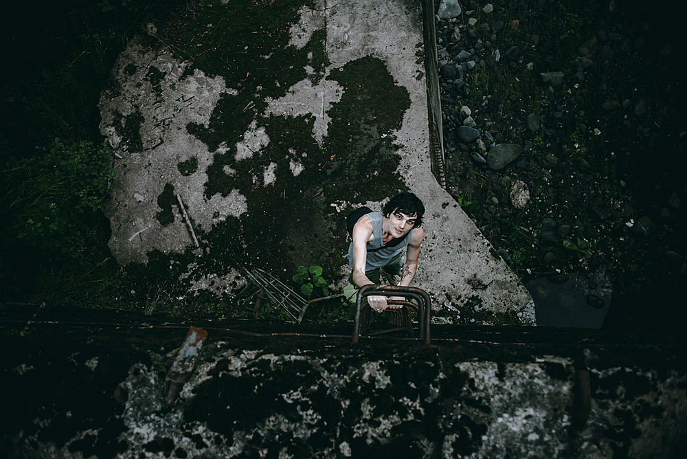 Caucasian man climbing ladder in concrete alley