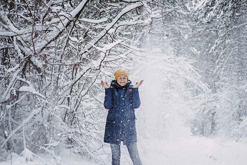 Snow falling on Caucasian woman in forest