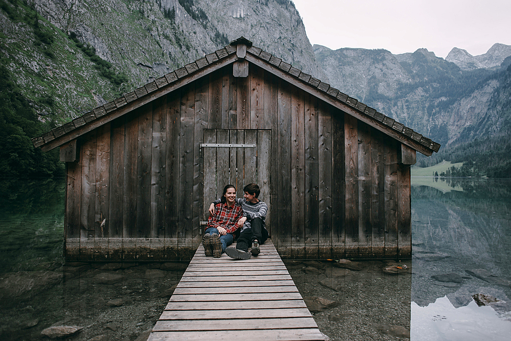 Caucasian couple sitting on dock at remote cabin