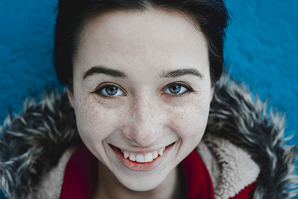 Smiling Caucasian woman near blue wall