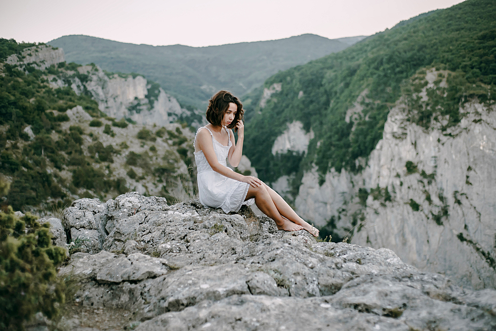 Pensive Caucasian woman sitting on mountain