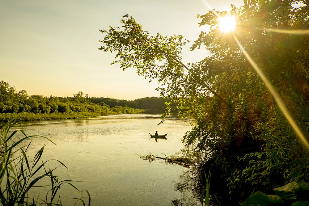 Distant Mari man fishing on lake, Ural, Russia