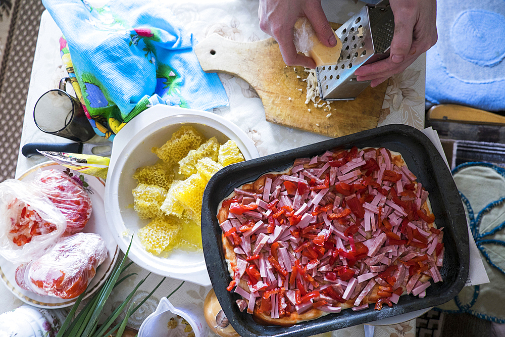 Hand grating cheese onto cutting board for pizza