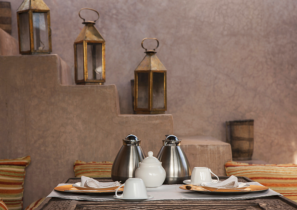 Coffee pots and plate at table near staircase