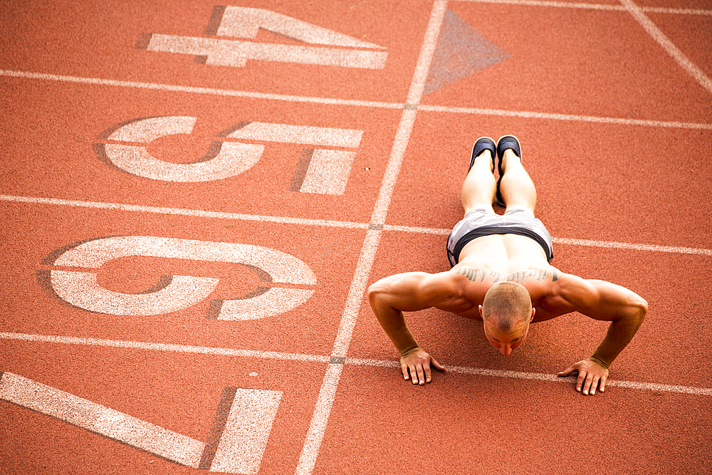 Caucasian man doing push-ups on running track