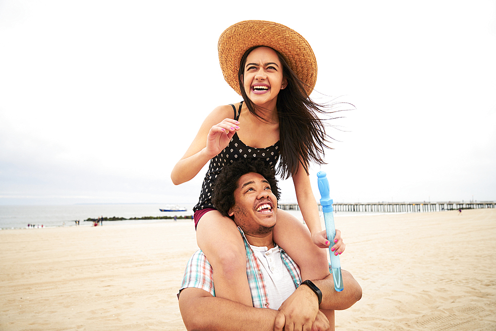 Man carrying woman on shoulders at beach