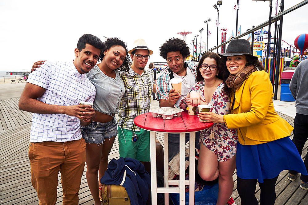 Friends drinking coffee on boardwalk at beach